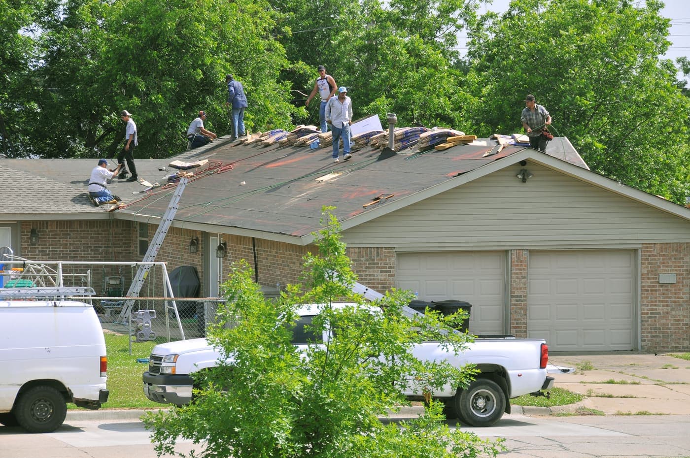 Repair crew replacing shingles on a storm-damaged residential roof