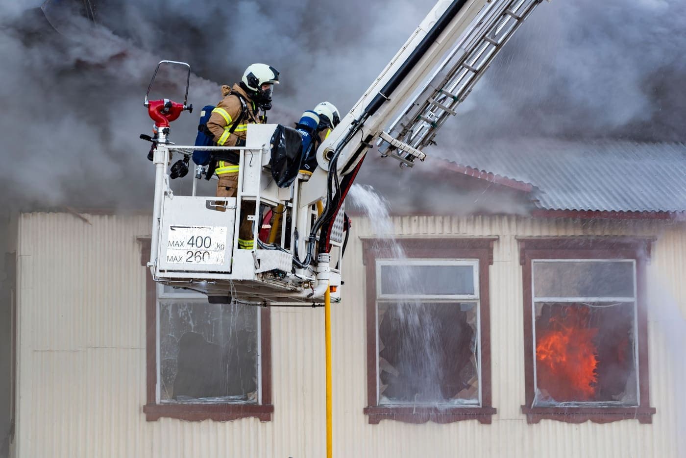 Firefighters spraying water into a burning house from a ladder platform