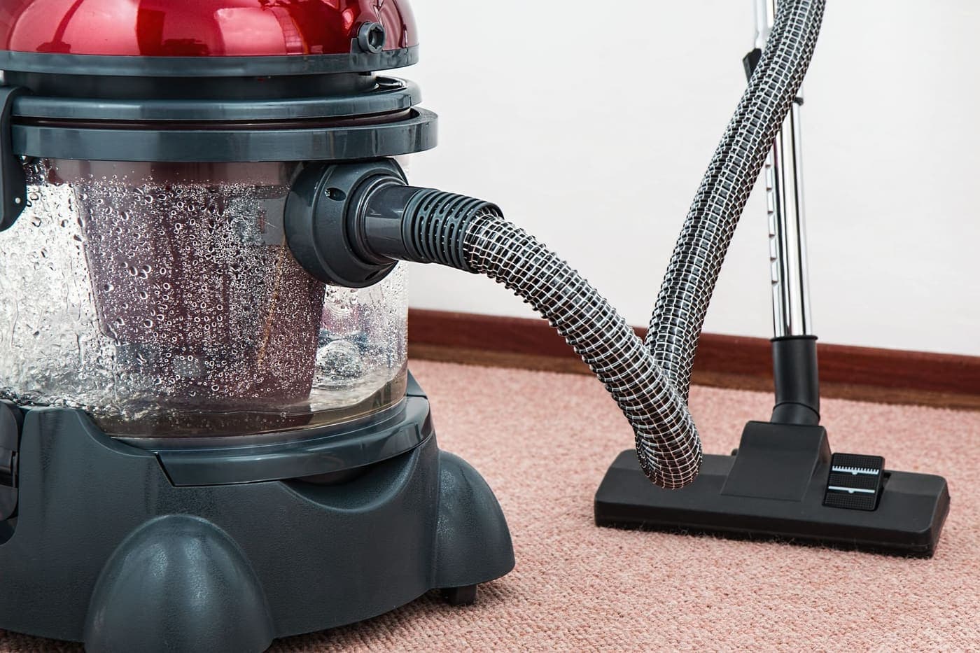 Wet extraction vacuum with water-filled tank on carpet