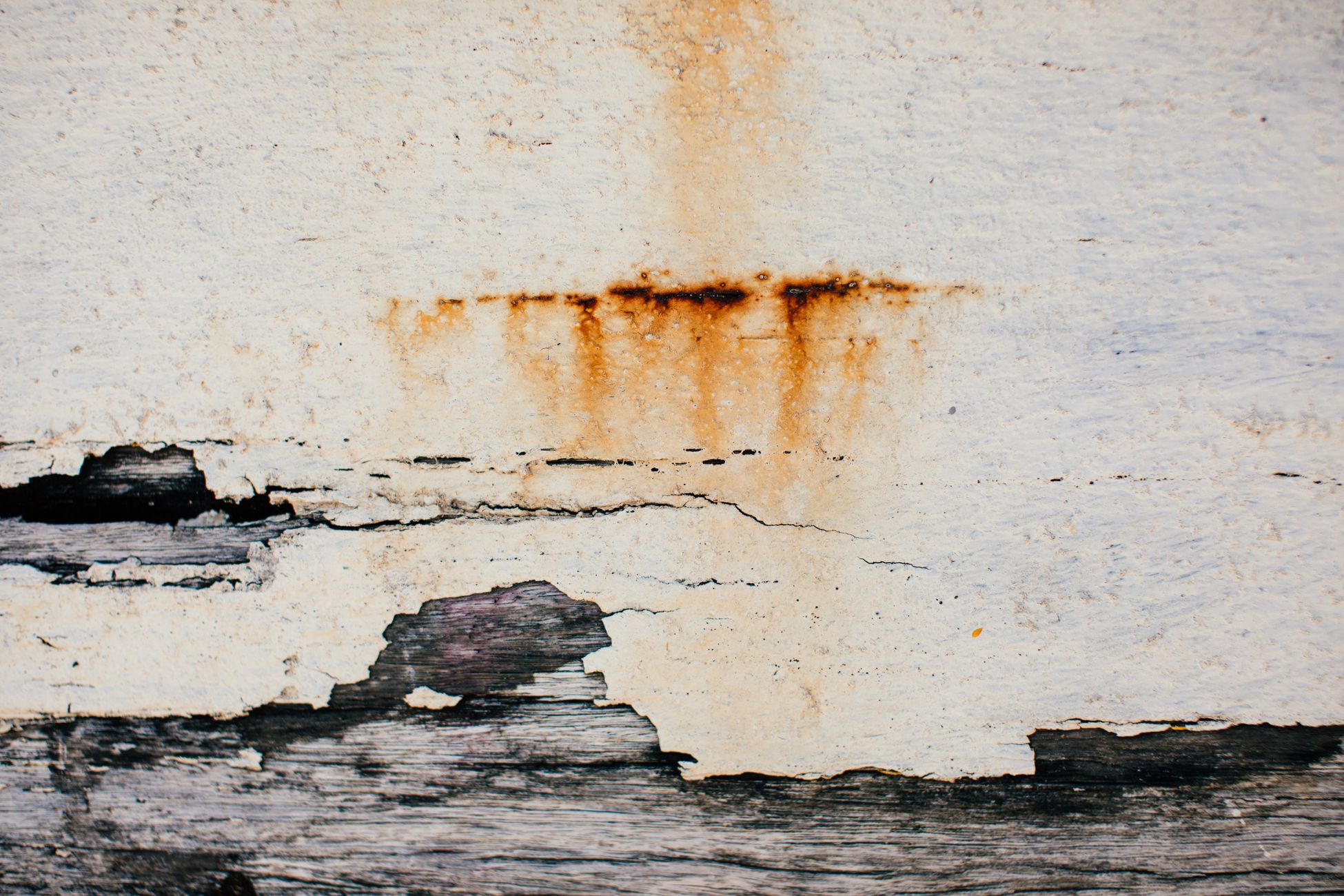 Rust-colored water stains bleeding through a ceiling surface