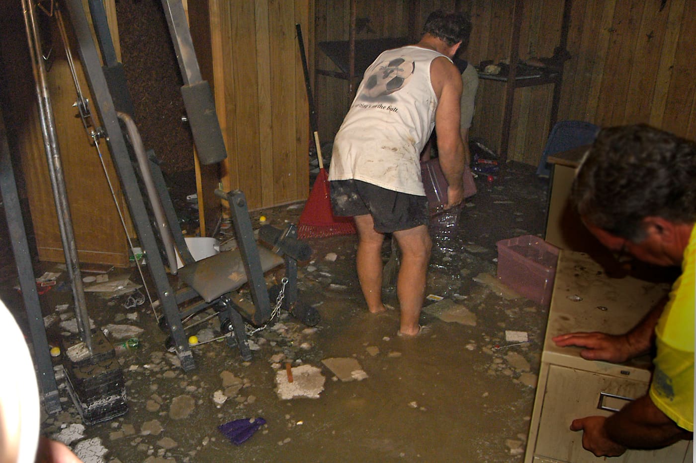 Homeowners removing standing water and soaked belongings from a flooded basement