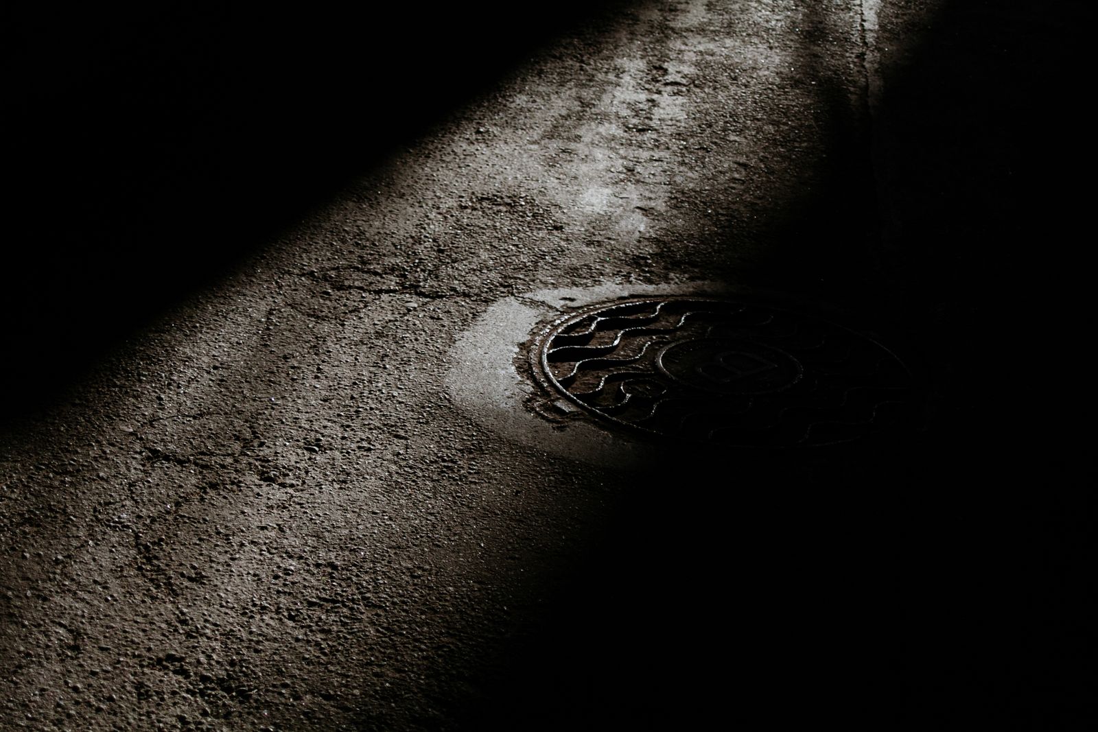 Sewer manhole cover on wet asphalt after a backup