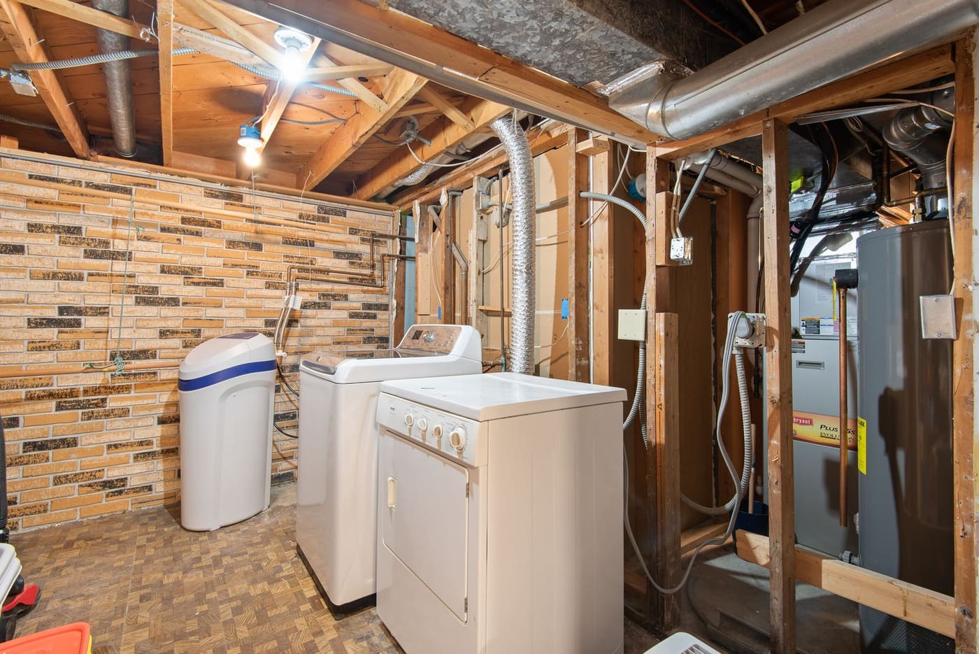 Water heater tank in an unfinished basement utility room beside laundry machines